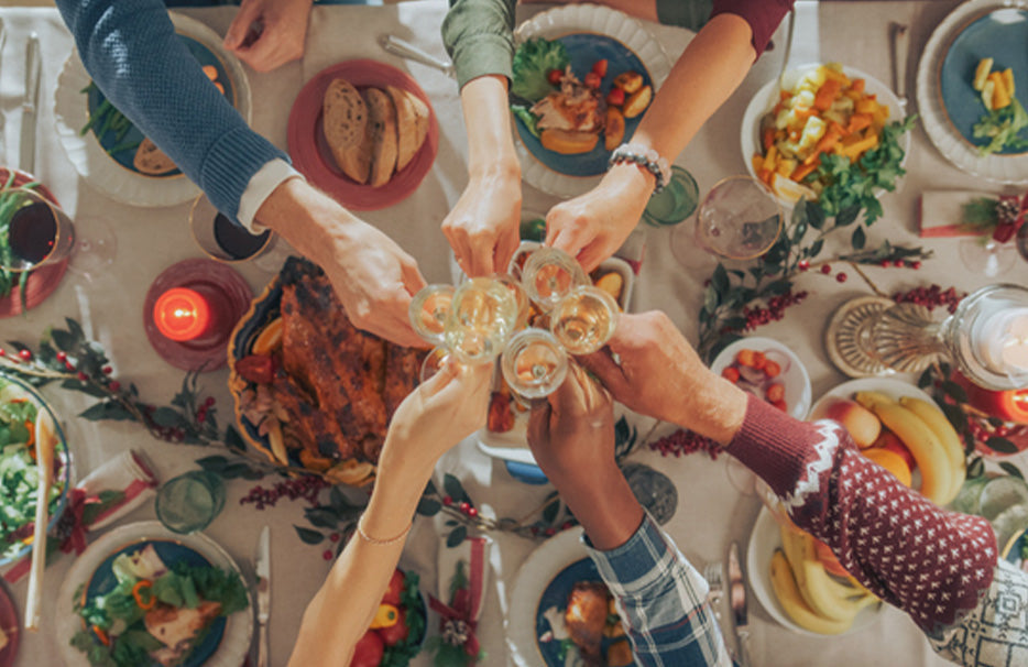 Pohľad zhora na slávnostne prestretý zimný stôl, pri ktorom si viacerí ľudia pripíjajú pohármi